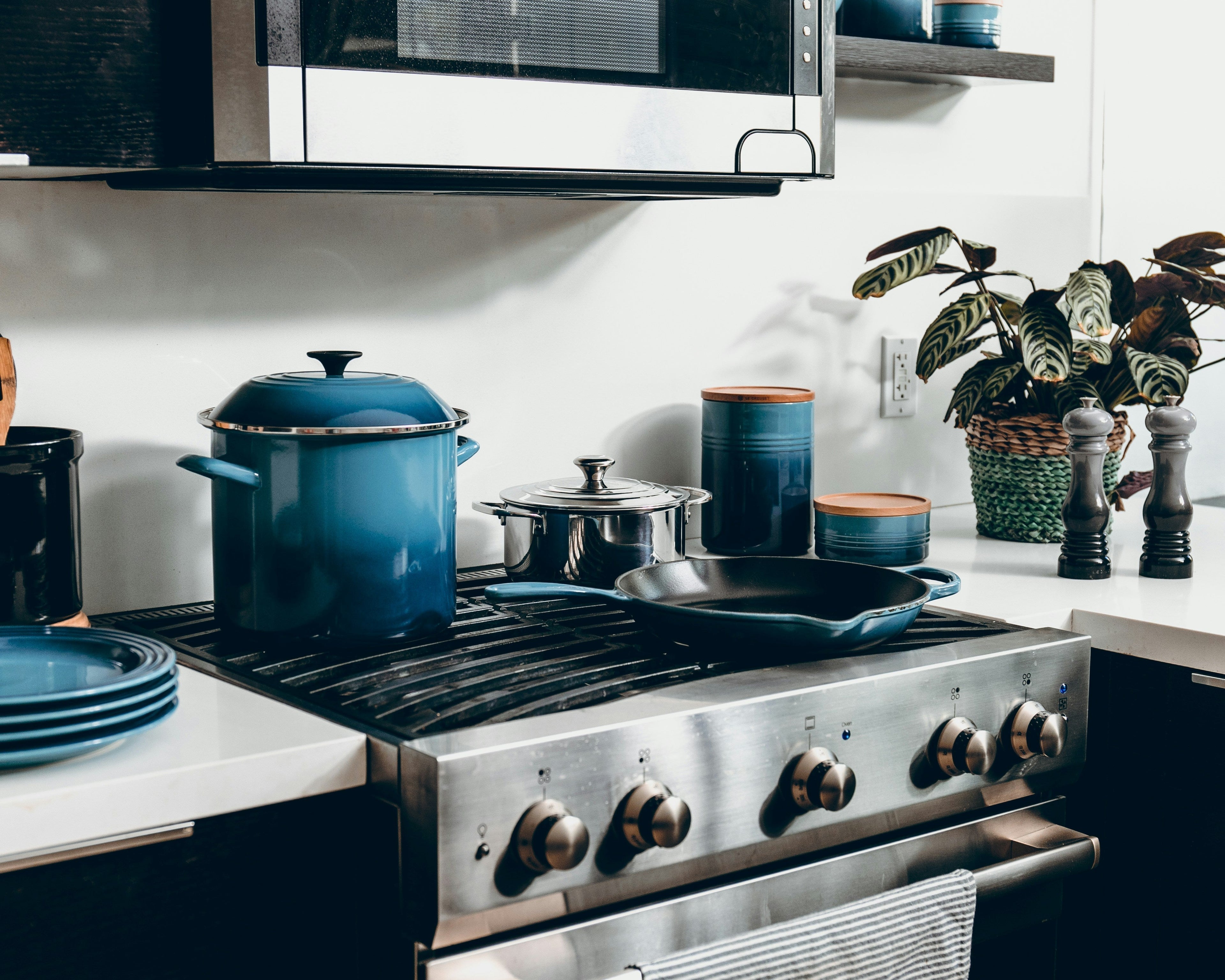 Kitchen gadgets including vegetable chopper, garlic press, and oil sprayer arranged on a clean kitchen countertop