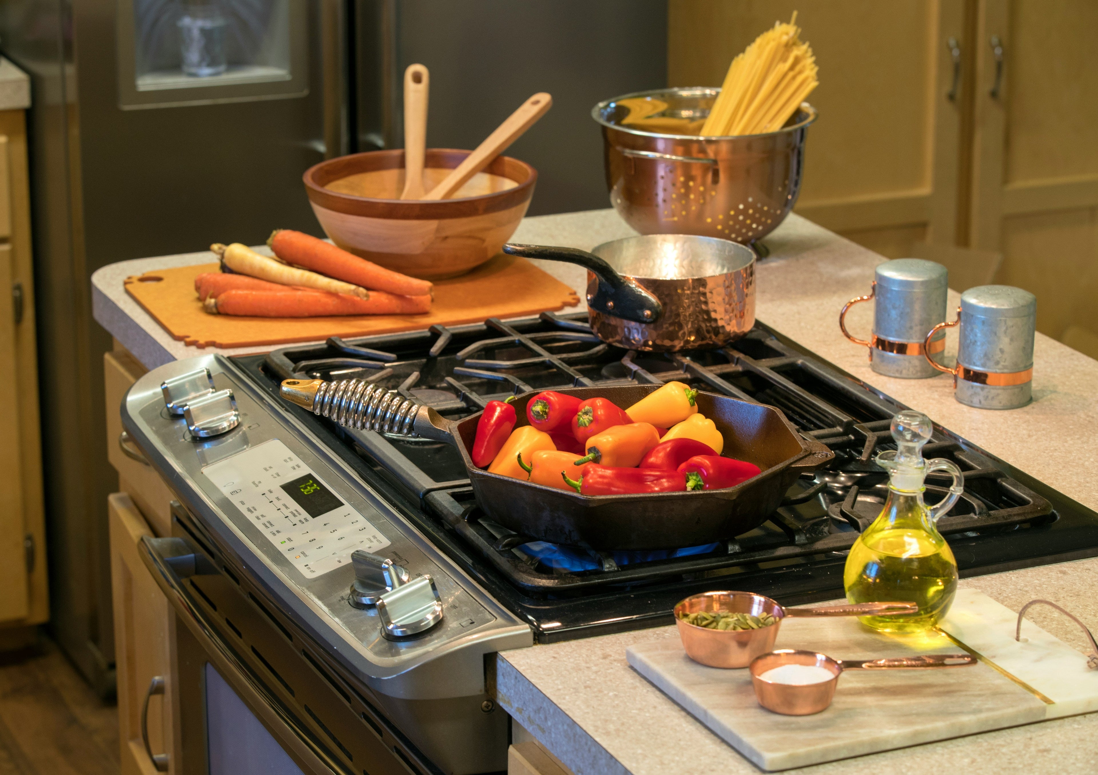 Kitchen gadgets including vegetable chopper, garlic press, and oil sprayer on a clean modern kitchen countertop